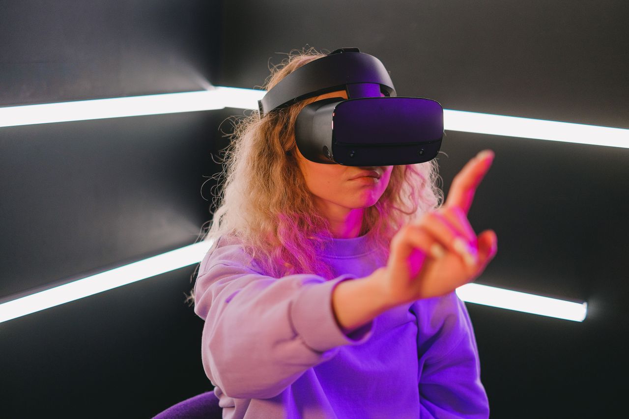 Young woman interacting with VR headset in a modern game room with neon lighting.